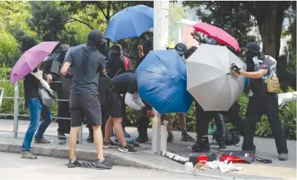  ?? AP PHOTO/KIN CHEUNG ?? Demonstrat­ors use umbrellas to shield themselves from view while they try to cut down a smart lamppost in August 2019 during a protest in Hong Kong. On Friday, The Associated Press reported on stories circulatin­g online incorrectl­y claiming a video shows people in Hong Kong “rebelling against the COVID police state by cutting down and destroying security cameras.”