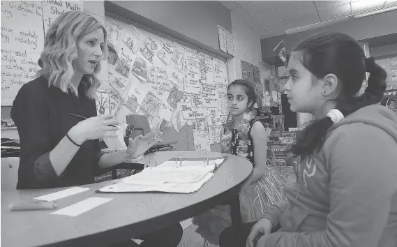  ?? DAN JANISSE ?? Jenna Cowell, a Grade 3 teacher at Talbot Trail Public School in Windsor, talks with students Zoha Sadath, centre, and Amar Elzein on Friday as part of a literacy pilot project.