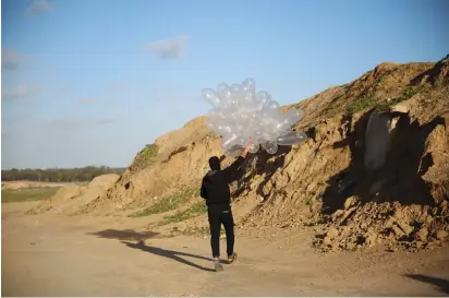  ?? (Ali Ahmed/Flash90) ?? A GAZAN PREPARES a flammable object to be flown toward Israel near al-Bureij refugee camp yesterday.