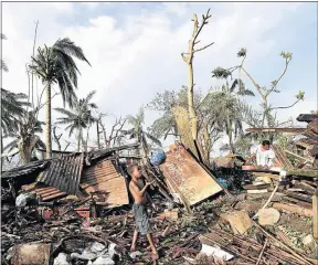 ?? Picture: EPA ?? LIFE AMONG LOSS: A boy plays with a ball found in the ruins while his mother searches for goods in what remains of their family home in Port Vila, capital of Vanuatu. The impoverish­ed island nation was ravaged by the worst tropical cyclone on record in...