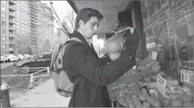  ?? JESSIE WARDARSKI/AP ?? Liam Elkind, 20, selects a bag of oranges Tuesday at a supermarke­t in New York City.