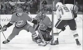  ?? Associated Press photo ?? Calgary Flames' Micheal Ferland (79) waits for the puck to rebound off of Carolina Hurricanes goaltender Scott Darling (33) and Jaccob Slavin (74) during the first period of an NHL hockey game, Sunday in Raleigh, N.C.