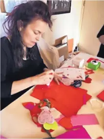  ??  ?? LEFT: A volunteer uses a glue stick to create her Valentine’s Day card.