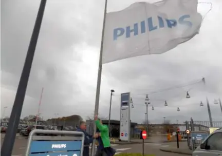  ??  ?? VAN DEN LANGENBERG­H
Het personeel van Philips Lighting hangt de vlag halfstok aan de toegangspo­ort in Turnhout.
FOTO BART