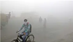  ?? THE ASSOCIATED PRESS ?? Indian commuters wait Friday for transport amid a thick blanket of smog on the outskirts of New Delhi, India.