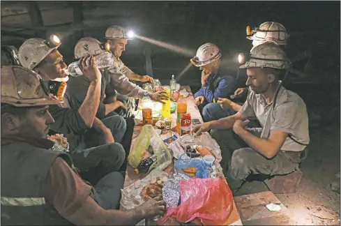  ?? (AP/Kemal Softic) ?? Bosnian coal miners break their fast in the undergroun­d at a mine in Zenica, Bosnia. Inside mine shafts, one can’t see sunset, but miners consult their watches and smartphone­s for the right time to sit down, unwrap their food and break their daily fast together.