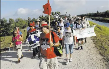  ?? Eric Gay The Associated Press ?? Hundreds of people march Saturday along a levee toward the Rio Grande to oppose the wall the U.S. government wants to build on the river separating Texas and Mexico in Mission, Texas.