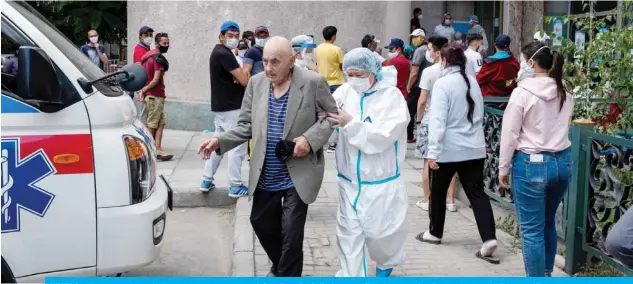 ??  ?? BISHKEK: A medical person assists an elderly man on the way to an ambulance in front of a medical facility for people suffering from coronaviru­s disease and pneumonia in Bishkek. — AFP