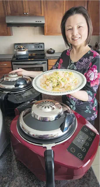  ?? WAYNE CUDDINGTON ?? Food blogger Lu Yang says she uses her Ropot, a made-in-Ottawa robotic cooking appliance, daily and it leaves her range hood “super clean” thanks to its ability to contain smoke and grease.