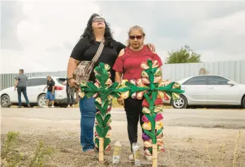  ?? JAY JANNER/AUSTIN AMERICAN-STATESMAN ?? Debra Ponce, left, and Angelita Olvera pray Tuesday in San Antonio near where officials said dozens of people were found dead after a tractor-trailer containing migrants was discovered a day earlier.