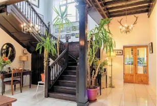  ??  ?? Clockwise from above: The Tudor Revival staircase in the hall; a water feature in the garden; the front door with a date plaque; Ned Kelly; the library has exposed ceiling beams and a wood-burning stove, and the kitchen