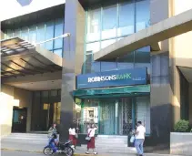  ?? BW FILE PHOTO ?? A MAN sits beside a Robinsons Bank branch in Manila.