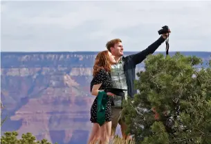  ?? MATT YORK THE ASSOCIATED PRESS ?? A couple takes a photo at the Grand Canyon in Arizona. Tourists are once again roaming portions of Grand Canyon National Park after it partially reopened Friday morning.