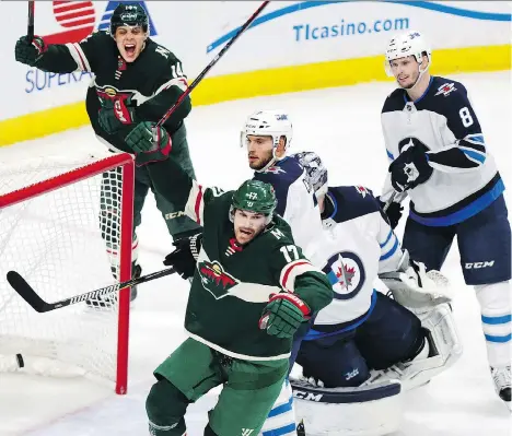  ?? ANDY CLAYTON-KING/THE ASSOCIATED PRESS ?? Minnesota Wild winger Marcus Foligno, bottom, and centreman Joel Eriksson Ek celebrate after Foligno scored a goal on Winnipeg Jets goaltender Connor Hellebuyck in the second period of Game 3 on Sunday in St. Paul, Minn.