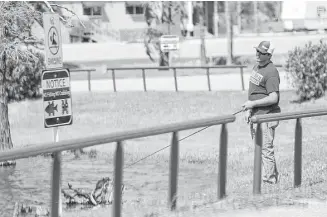  ?? Elizabeth Conley / Houston Chronicle ?? A fisherman checks out the signs that tell people not to fish or crab at River Terrace Park in Channelvie­w. A dioxin hot spot in river sediments is near the park.