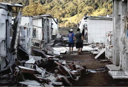  ?? Pedro Ladeira/folhapress ?? Moradores caminham dentro de cemitério destruído pela enchente na cidade de Muçum (RS)