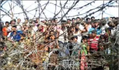  ?? YE AUNG THU/AFP ?? Rohingya refugees gather behind a barbed-wire fence in a temporary settlement setup in a ‘no man’s land’ border zone between Myanmar and Bangladesh on April 25.