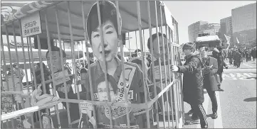  ?? — AFP photo ?? Anti-government activists carrying a mock prison containing a board-cut of Park march toward the presidenti­al Blue House after the announceme­nt of the Constituti­onal Court’s decision to uphold the impeachmen­t of Park in Seoul.