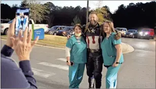  ??  ?? Nick Sergent, dressed as Captain America, poses for a picture with his wife Mary, right, and Courtney Burger during the community prayer event Thursday evening.