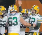  ?? Nam Y. Huh The Associated Press ?? Packers quarterbac­k Aaron Rodgers (12) joins teammates to celebrate Aaron Jones’ touchdown run in Green Bay’s rout of the Bears to clinch the NFC’S top seed.