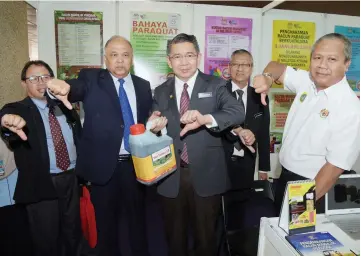  ??  ?? Salahuddin (centre) gives the thumbs-down with others during his visit to the exhibition hall after officiatin­g at the launch of a campaign on the paraquat ban. — Bernama photo