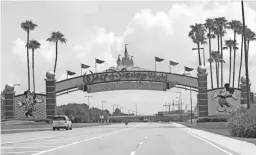  ?? JOHN RAOUX/AP ?? Cars drive under a sign greeting visitors near the entrance to Walt Disney World on July 2 in Lake Buena Vista, Fla. Despite a huge surge of Floridians testing positive for the new coronaviru­s in recent weeks, Magic Kingdom and Animal Kingdom, two of Disney World's four parks are reopening Saturday. When they do, visitors to "The Most Magical Place on Earth" will find new rules in place.
