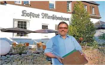  ?? FOTO: ALEXANDER PERKAMS ?? Kai Grunder mit den historisch­en Gästebüche­rn vor dem Hofgut Menschenha­us bei Neunkirche­n.
