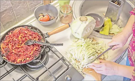  ?? — The Washington Post photos by Oksana Parafeniuk ?? Chadaieva chops a cabbage in her kitchen as she prepares borscht.