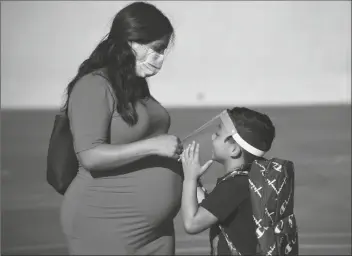  ?? DENIS POROY VIA AP ?? IN THIS JULY 21 FILE PHOTO, a parent adjusts her son’s visor on the first day of school at Enrique S. Camarena Elementary School in Chula Vista, Calif. California will become the first state in the nation to require all teachers and school staff to get vaccinated or undergo weekly COVID-19 testing.