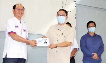  ??  ?? Tangau (left) presenting an assistance to a church leader during his visit to Kg Sinalapak.