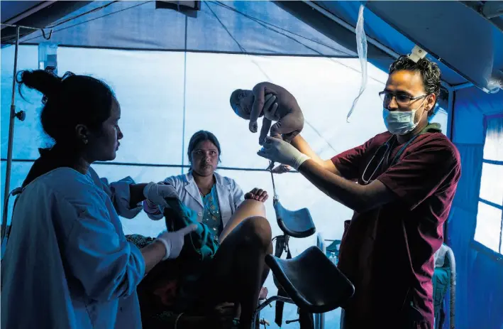  ??  ?? Dr. Binod Dangal delivers a baby boy to Durga Shrestha in a tent at Gauri Shanker Hospital in Pakhalati, Nepal, on May 22, in the aftermath of the country’s devastatin­g earthquake­s.