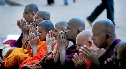  ?? AP ?? Buddhist monks pray during a ceremony to invoke blessings on the dead and wounded from Sunday’s bombings at the Kelaniya temple in Colombo.