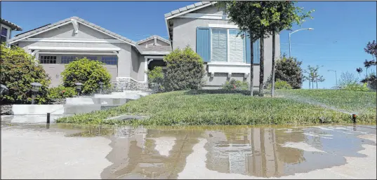  ?? Rich Pedroncell­i The Associated Press file ?? Water flows down a sidewalk from sprinklers at a home in 2015 in Rancho Cordova, Calif. The State Water Resources Control Board voted Tuesday for a rule to prohibit excessive runoff from sprinklers.