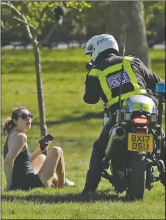  ?? (File Photo/AP/Matt Dunham) ?? A woman is told to go home in April by a police officer on a motorbike to stop the spread of coronaviru­s and keep the park open for people observing the British government’s guidance of social distancing, only using parks for dog walking or one form of exercise a day, such as a run, walk, or bike ride alone or with members of the same household, on Primrose Hill in London.