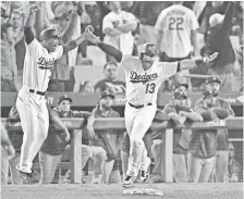  ?? JAYNE KAMIN-ONCEA/USA TODAY ?? Max Muncy and first-base coach George Lombard celebrate after the homer that gave the Dodgers their only win in the series.