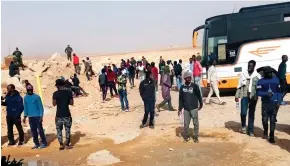  ??  ?? Expulsion: Soldiers, far left, guard migrants in the Algerian desert...