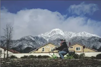  ?? ASSOCIATED PRESS ?? A CYCLIST RIDES A BIKE ALONG THE PACIFIC ELECTRIC TRAIL in Rancho Cucamonga, Calif. against a backdrop of the snow-capped San Gabriel Mountains on Monday.