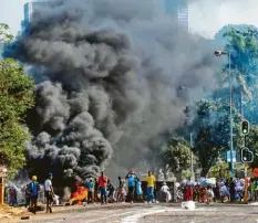  ?? Foto: Andre Swart, dpa ?? In Südafrika eskaliert die Gewalt: Plünderer stehen vor einem Einkaufsze­ntrum in Durban neben einer brennenden Barrikade.