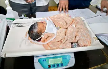  ?? — PTI ?? A new-born baby wearing a protective mask in the wake of coronaviru­s pandemic being weighed at Hailate Hospital in Kanpur on Friday.