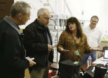  ?? RICK WILKING/REUTERS ?? Cheri Hackett, second from right, co-owner of the Botana Care marijuana store, talks to Colorado Marijuana Enforcemen­t officials just before opening her doors to customers for the first time in Northglenn, Colo.