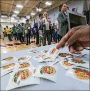  ?? JOHN SPINK /JSPINK@AJC.COM ?? A poll worker hands out stickers to voters in 2016.