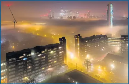  ??  ?? A thick blanket of fog covers the Canary Wharf area of east London yesterday as temperatur­es plunged