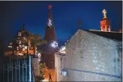  ?? (AP/Oded Balilty) ?? A man walks by a Christmas tree Dec. 12 during the lighting ceremony outside the Greek Orthodox Church of the Annunciati­on in Nazareth, Israel.