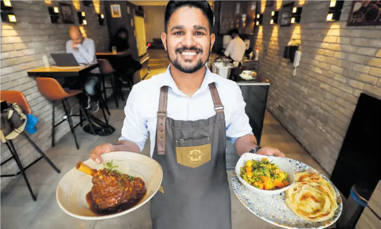  ?? ?? Osmijeh je zaštitni znak indijskog bistroa u Preradović­evoj. Konobar Prasad Deepak Tambe (24) s indijskim specijalit­etima lamb shankom i vegetarija­nskom kormom. Glavni je chef Namaste Bistroa Harshad Kishor Arekar (34) – u pozadini