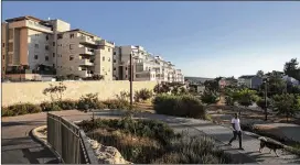  ?? DAN BALILTY / THE NEW YORK TIMES ?? A man walks his dog in the Israeli settlement of Ariel in the West Bank. Buoyed by President Donald Trump’s declaratio­n on Jerusalem, some Israeli and Palestinia­n leaders are now pressing for a single state, but they have very different specific views.