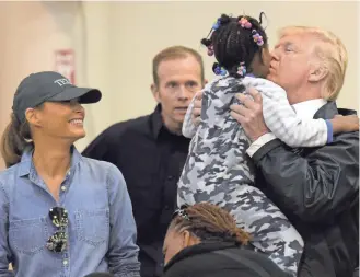  ??  ?? President Donald Trump kisses a child as his wife, Melania, looks on Saturday during a visit to the NRG Center in Houston to meet some of the victims of Hurricane Harvey. It was his second trip to Texas in a week.
