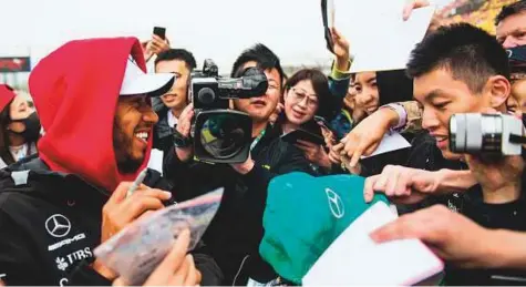  ?? AFP ?? Mercedes’ Lewis Hamilton signs autographs prior to the Formula One Chinese Grand Prix in Shanghai yesterday.