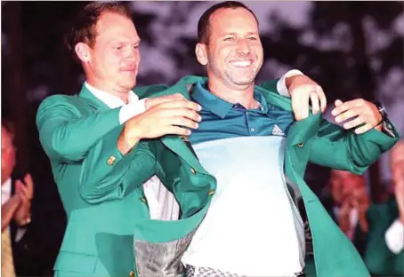  ??  ?? From one champion to another... last year’s winner, Danny Willett (left), helping Sergio Garcia into the Green Jacket… Sunday night
