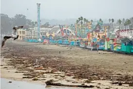  ?? MARIO TAMA/GETTY ?? Storm debris washes up in front of the boardwalk amusement park Wednesday in Santa Cruz, California. Storms are continuing to drench much of Northern California.