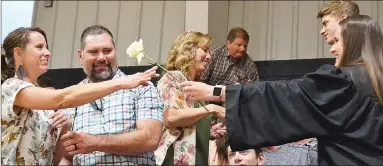  ?? TIMES photograph­s by Annette Beard ?? Graduate Emma Stein (far right) gives a flower to her parents Beth Stein and John Stein at Baccalaure­ate Friday night. Graduate Nick Coble (second from right) hands a flower to his mother, Susan.